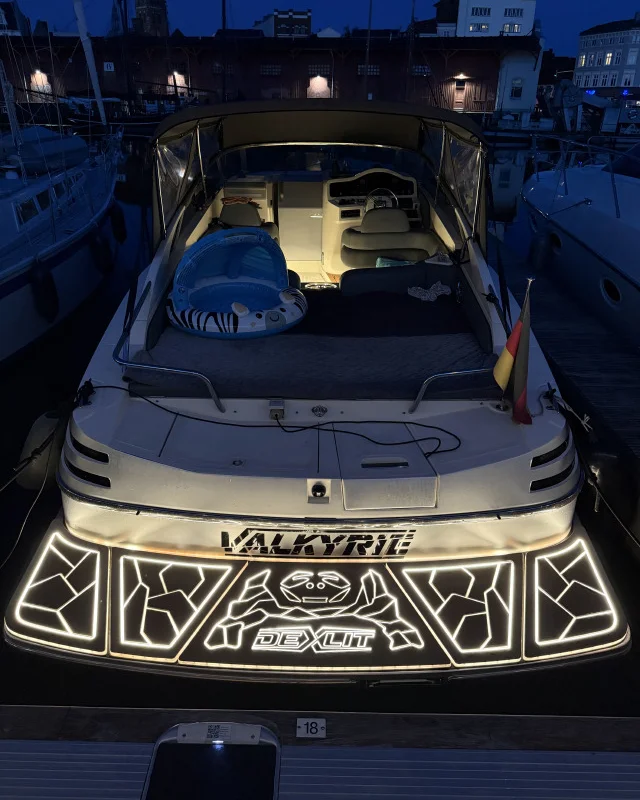 Motor yacht swim platform with DEXLIT illuminated pattern and logo at night.